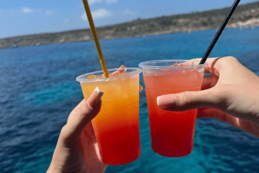 Two colourful drinks held up over the sea on a Cyprus catamaran cruise