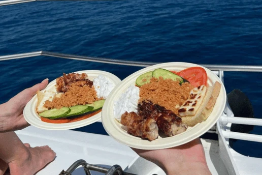 Plates of grilled chicken, halloumi, pourgouri and salad served on board a SCUBACAT cruise