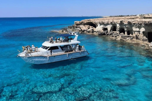 Catamaran with passengers anchored beside the sea caves at Cape Greco, Cyprus