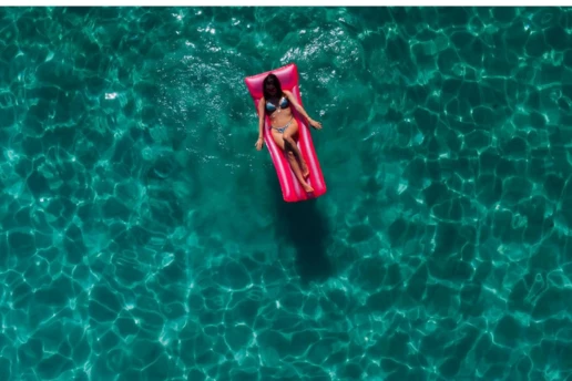 Woman relaxing on a pink inflatable float in the clear turquoise water of the Blue Lagoon