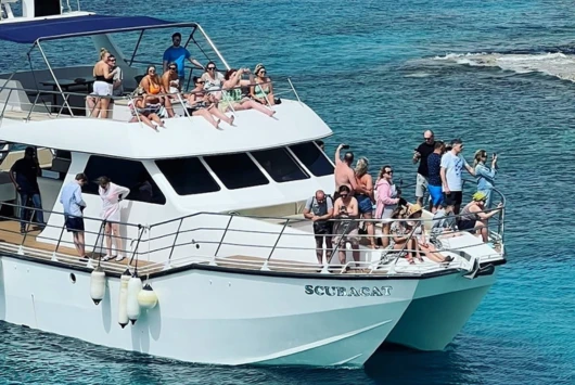 Guests relaxing on the deck of the SCUBACAT catamaran in clear turquoise water near Ayia Napa