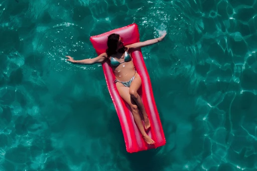 Woman relaxing on a pink inflatable float in the clear turquoise sea during a SCUBACAT catamaran cruise