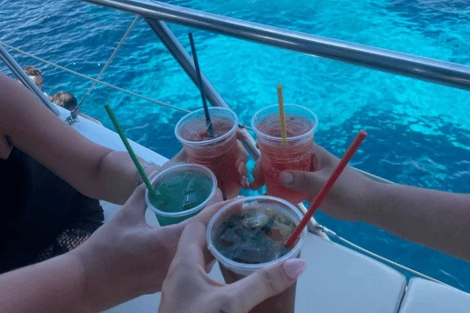 Group of friends toasting with drinks over the clear blue water on a Cyprus cruise