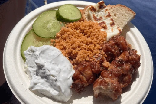 Plate of grilled chicken souvlaki, pourgouri, halloumi, tzatziki and cucumber on a SCUBACAT cruise