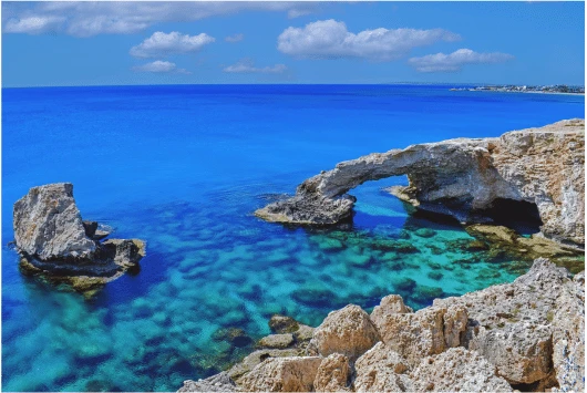 Natural rock arch over clear blue water on the Cape Greco coastline, Cyprus