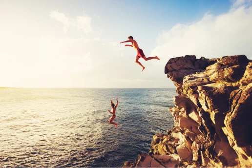 Two people cliff jumping into the sea at sunset, the kind of jump now closed at the Ayia Napa Sea Caves