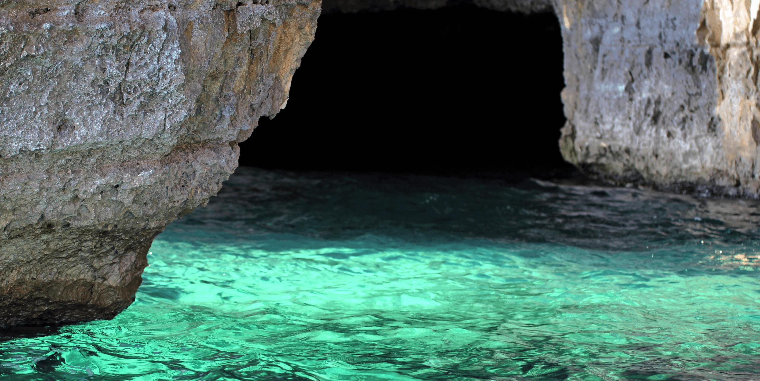Turquoise water glowing at the entrance to a sea cave at Cape Greco near Ayia Napa