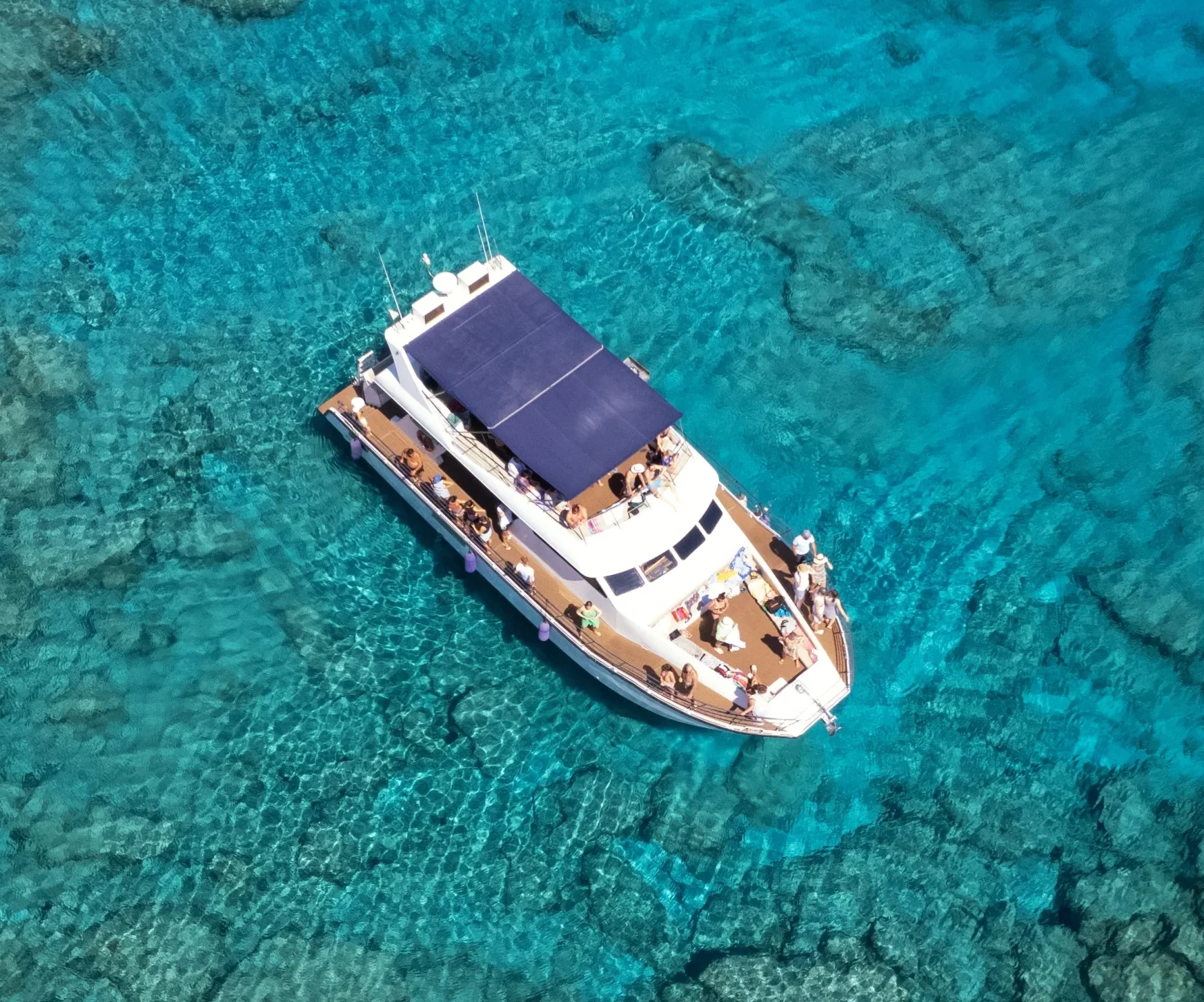Catamaran anchored over clear turquoise water near Cape Greco, seen from above