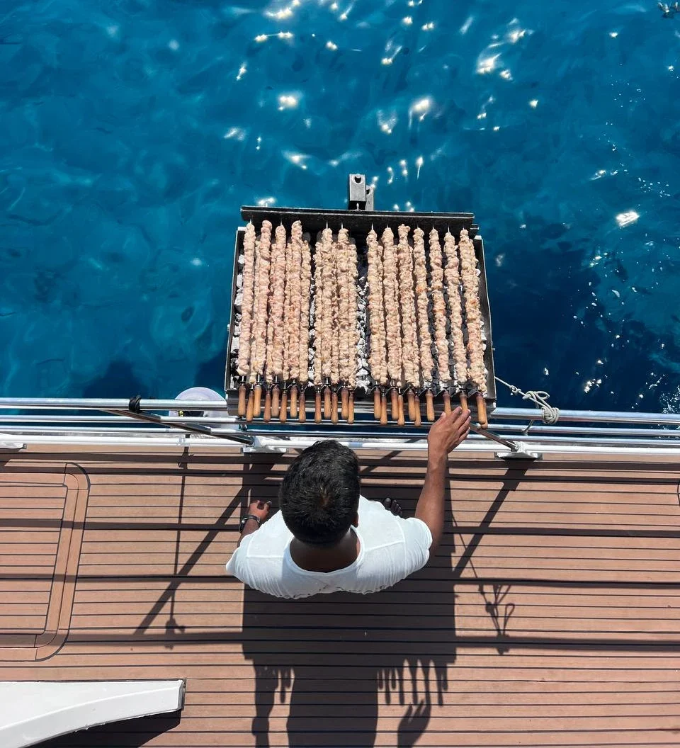 Crew member grilling fresh chicken souvlaki on the back deck of the SCUBACAT catamaran