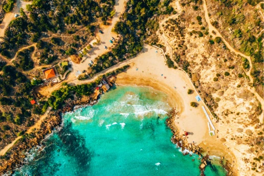 Aerial view of the horseshoe-shaped Konnos Bay and its sandy beach inside Cape Greco park
