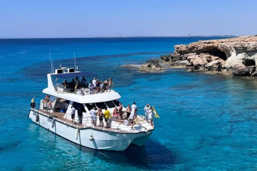SCUBACAT catamaran with guests on deck cruising the turquoise Cape Greco coastline near Ayia Napa