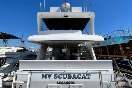 Stern of the MV Scubacat, with Limassol as its port of registry, moored beside other boats in a harbour